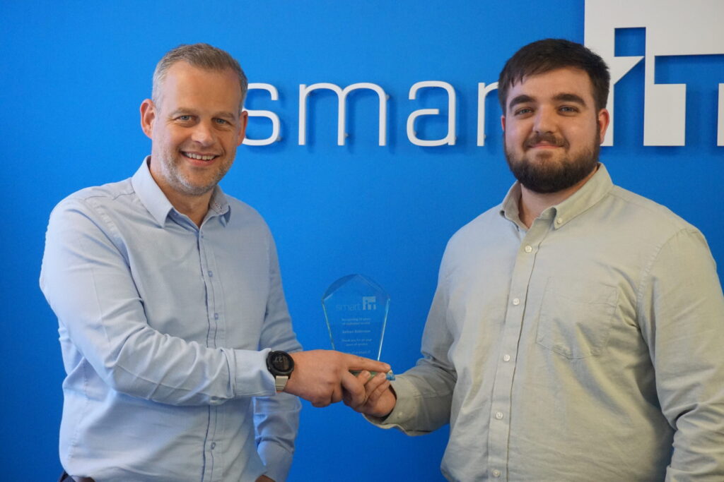 Two men shaking hands during an award presentation at Smart IT.