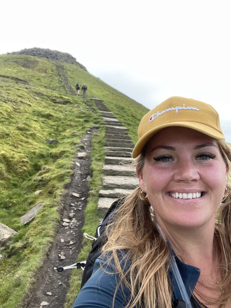 Smiling woman in yellow cap on hiking trail at Yorkshire Three Peaks.