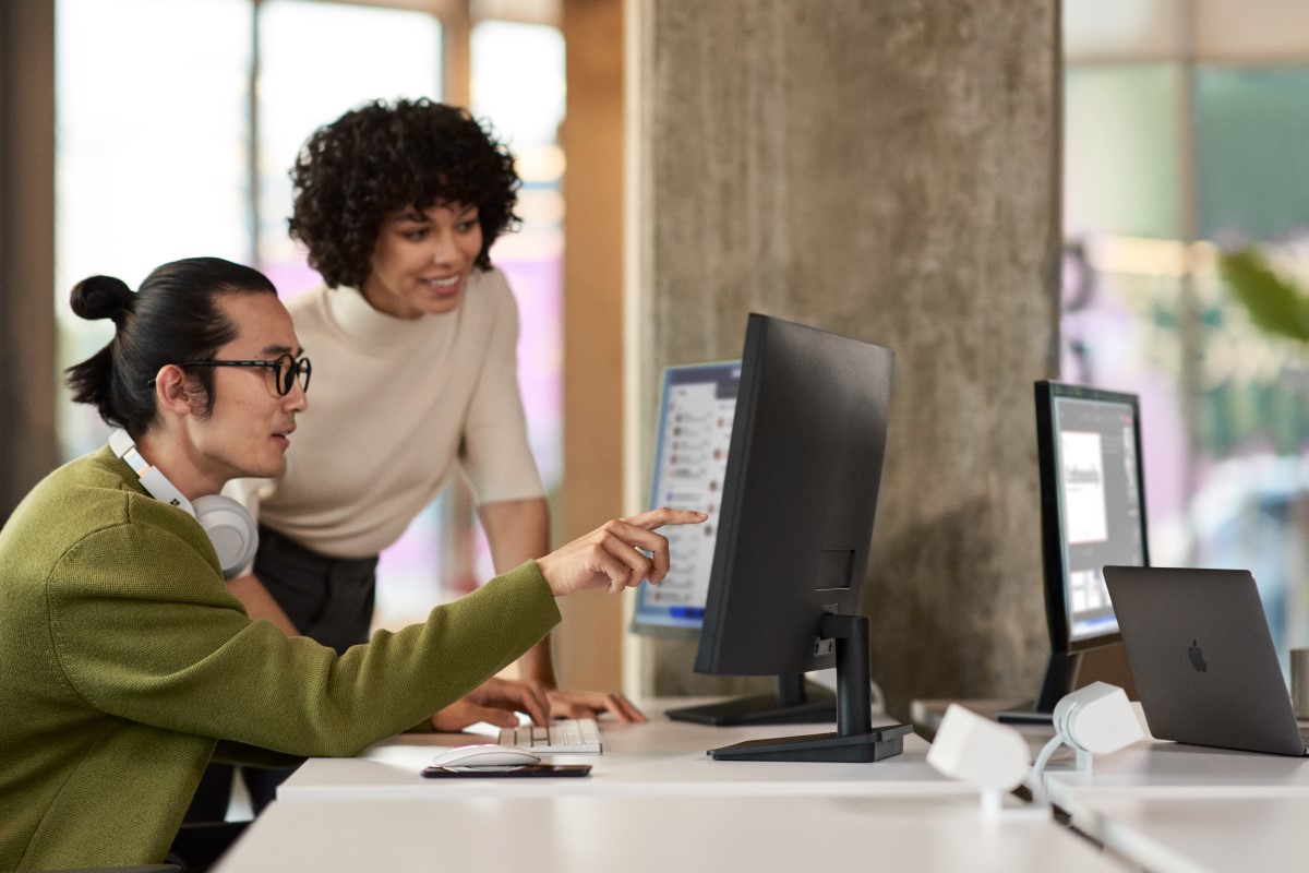 Two women collaborating on a computer in a modern office environment.